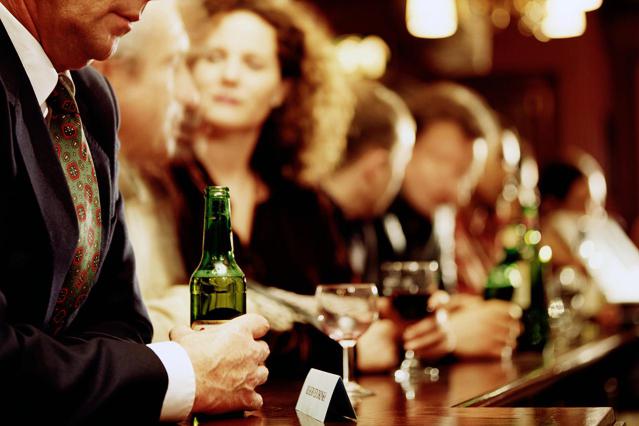 professional looking male drinking a bottle of beer in a pub