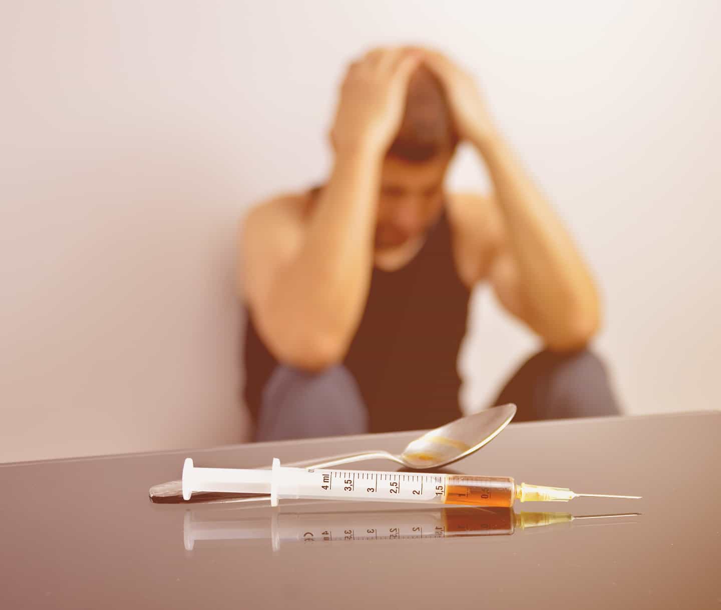 man looking stressed with drug paraphernalia on the foreground