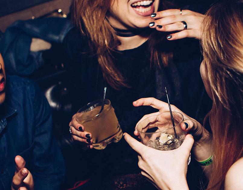 girls holding alcoholic drinks at a party - signs of alcohol addiction
