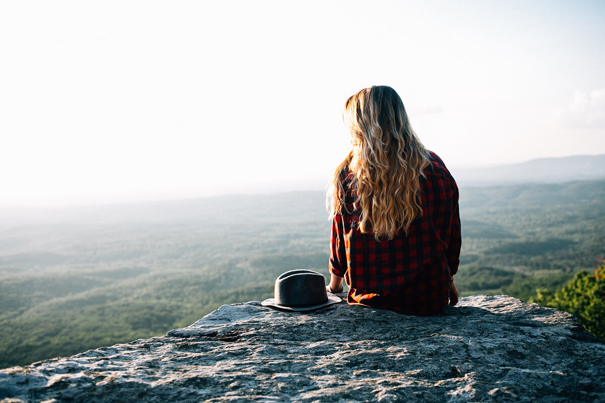 a woman is setting at the edge and considering to travel for the abroad rehab.