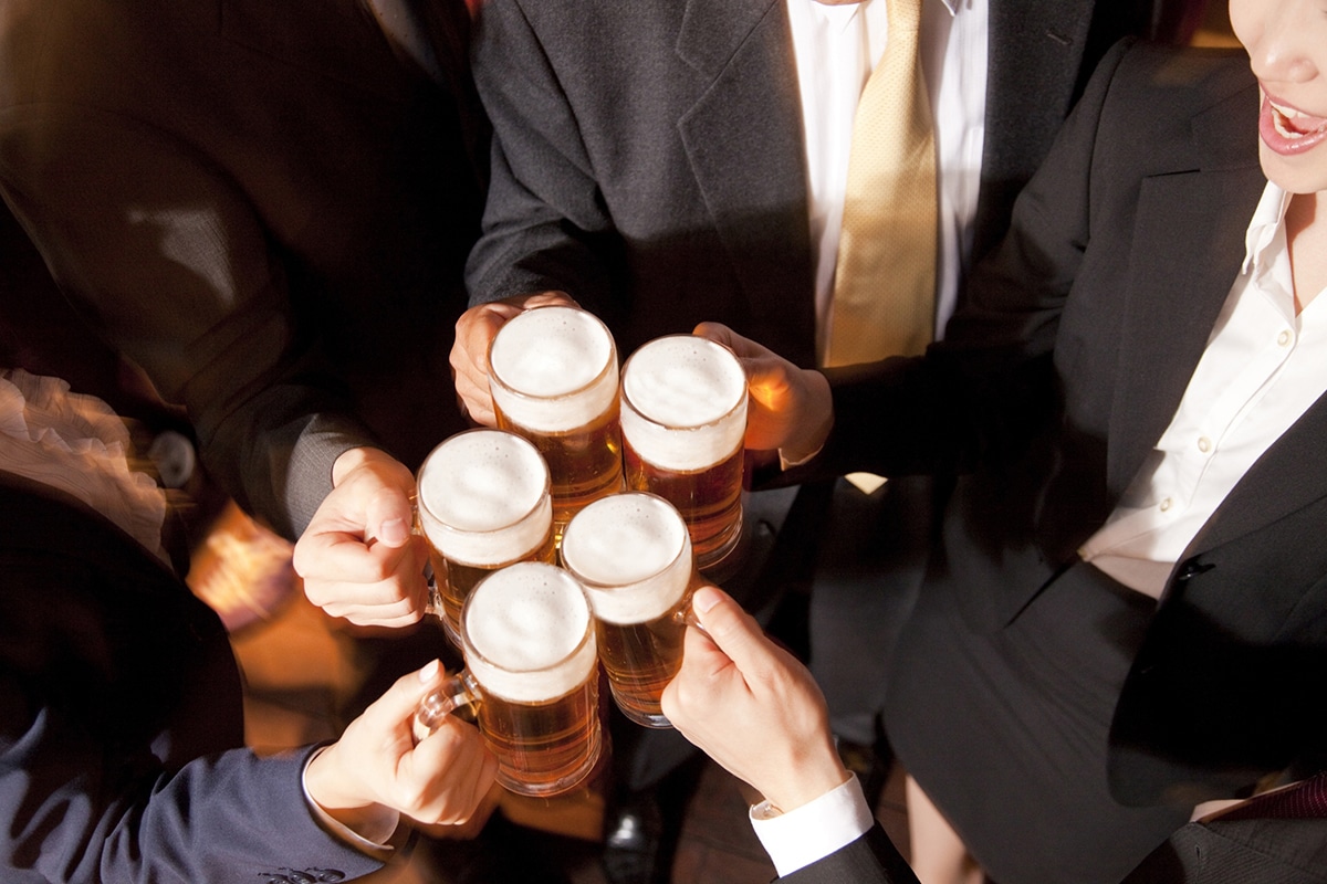 Several professionals drink beers together at a bar after work.