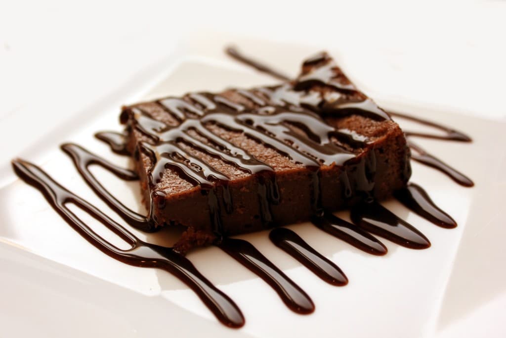 A brownie topped with chocolate syrup served on a plate