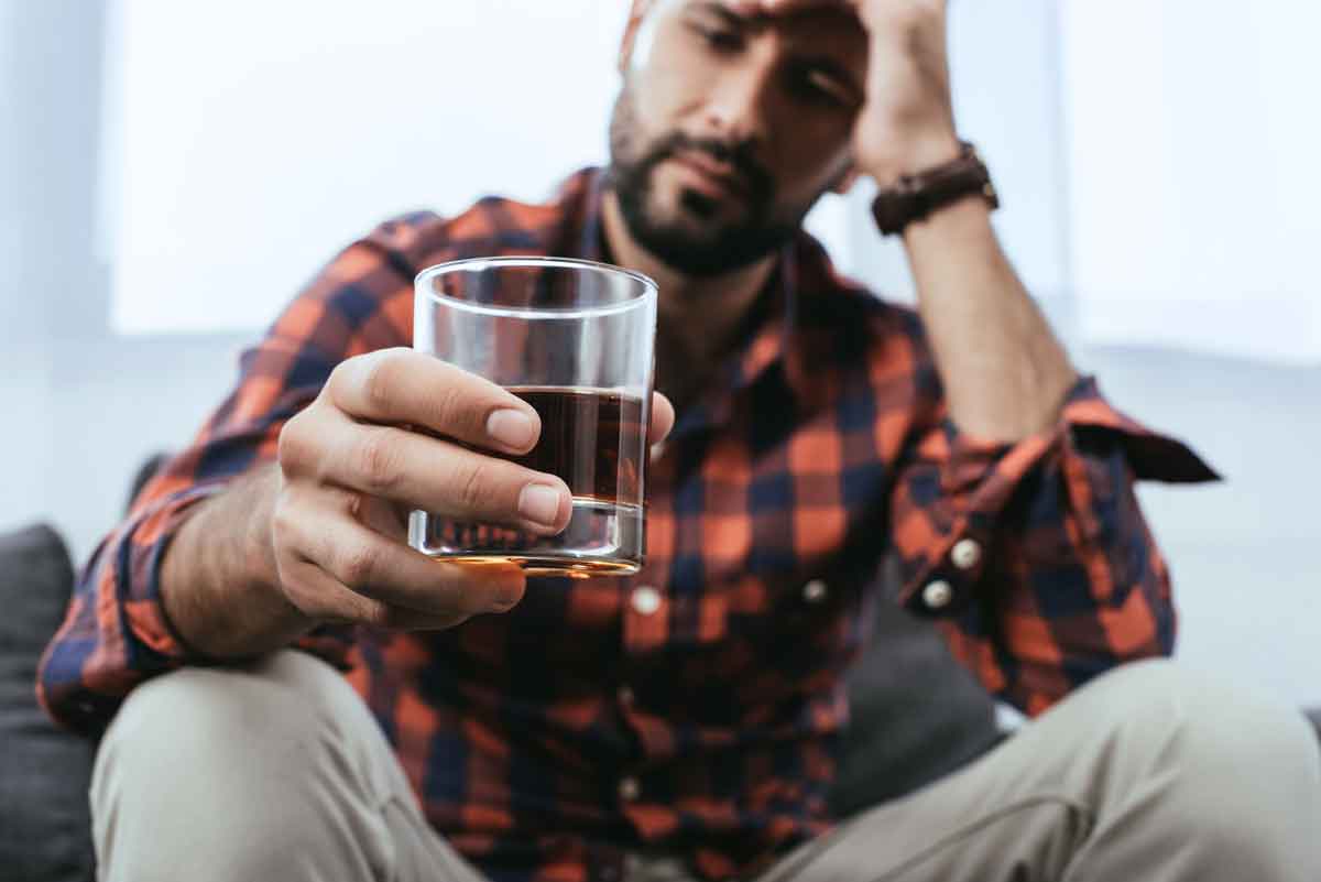 a man drinking alcohol at home alone