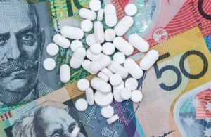 Handful of pills scattered on top of Australian dollar bills