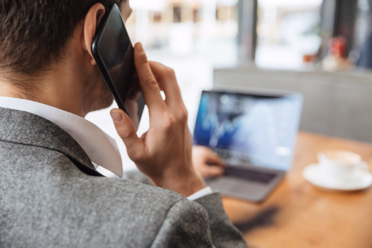 cropped image businessman sitting by table cafe analyzing indicators laptop computer while talking by smartphone focus man - Travel procedure