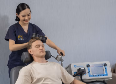 A female nurse doing TMS therapy to a male client