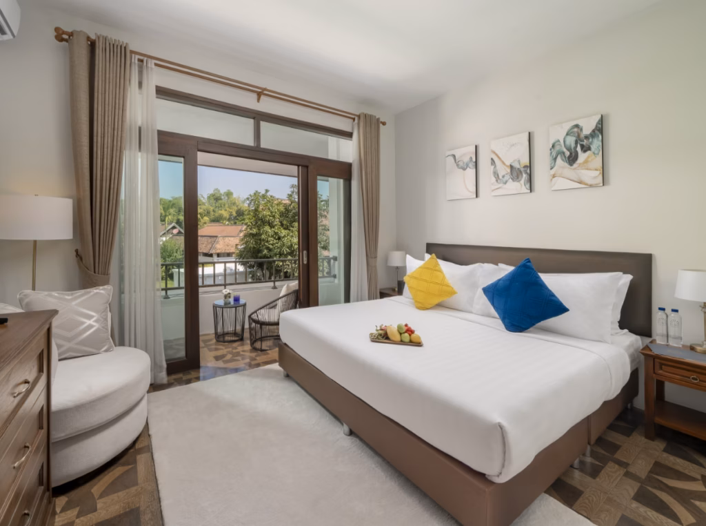 A bedroom with a king sized bed covered in white sheets and blue and yellow pillows
