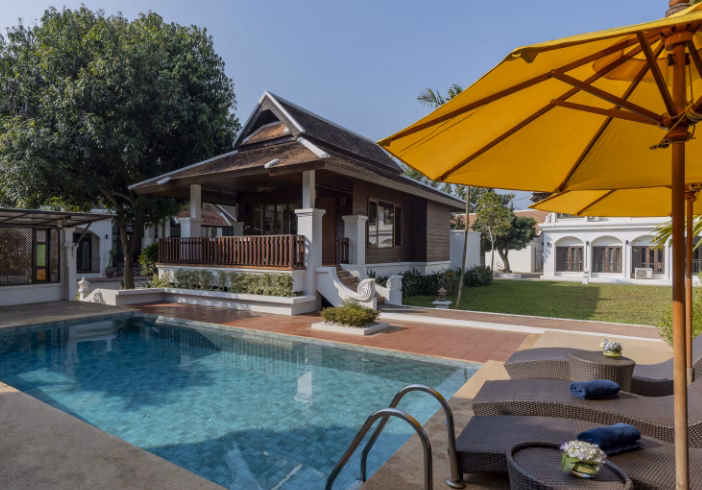 A pool with a yellow umbrella in front of a traditional Thai house - EMDR Therapy Thailand | Effective Trauma Treatment at The Dawn